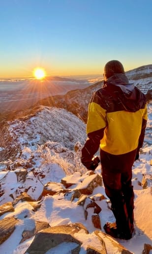 雪山登山中に日の出を見ている写真